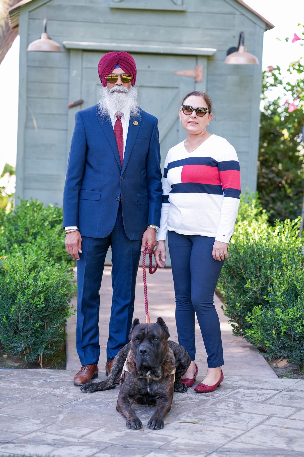 Gurjant Singh Khosa with his wife and their dog outside a green barn