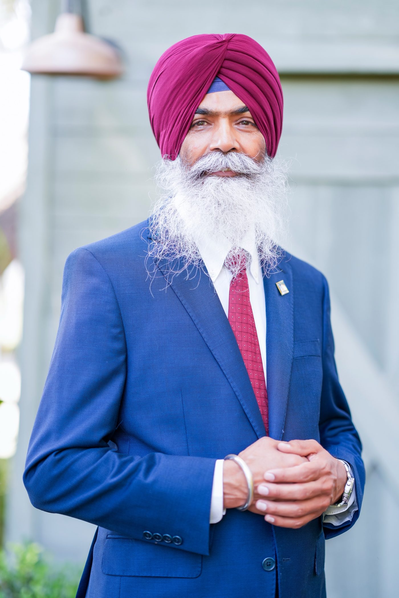 Gurjant Singh Khosa in a navy suit and maroon dastaar, smiling warmly